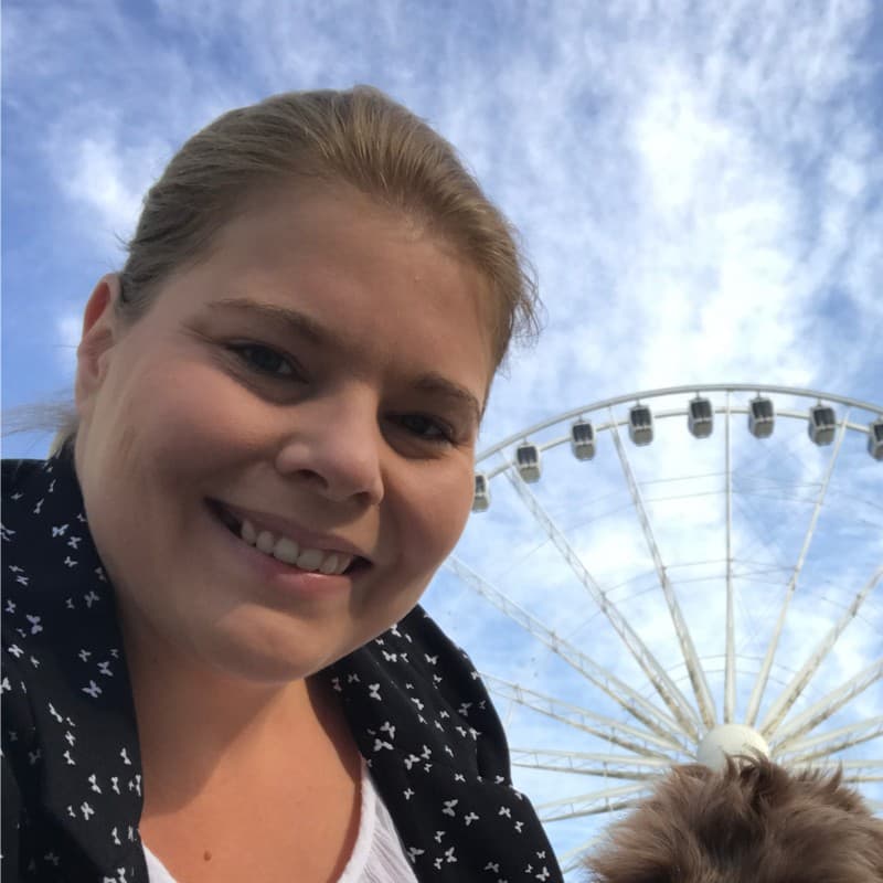 A smiling woman outdoors with a Ferris wheel behind her